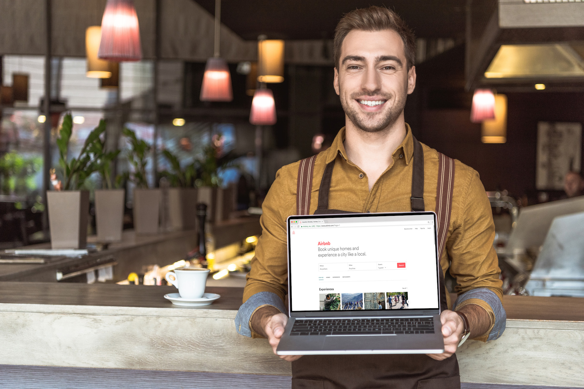 handsome-young-waiter-holding-laptop-with-airbnb-w-2022-12-16-15-43-06-utc